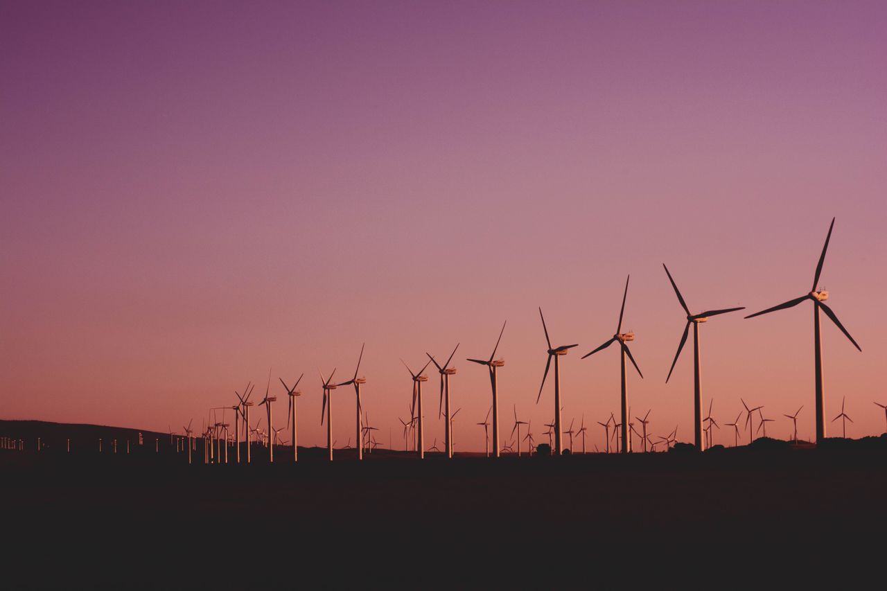 A row of wind turbines on a hill at sunset